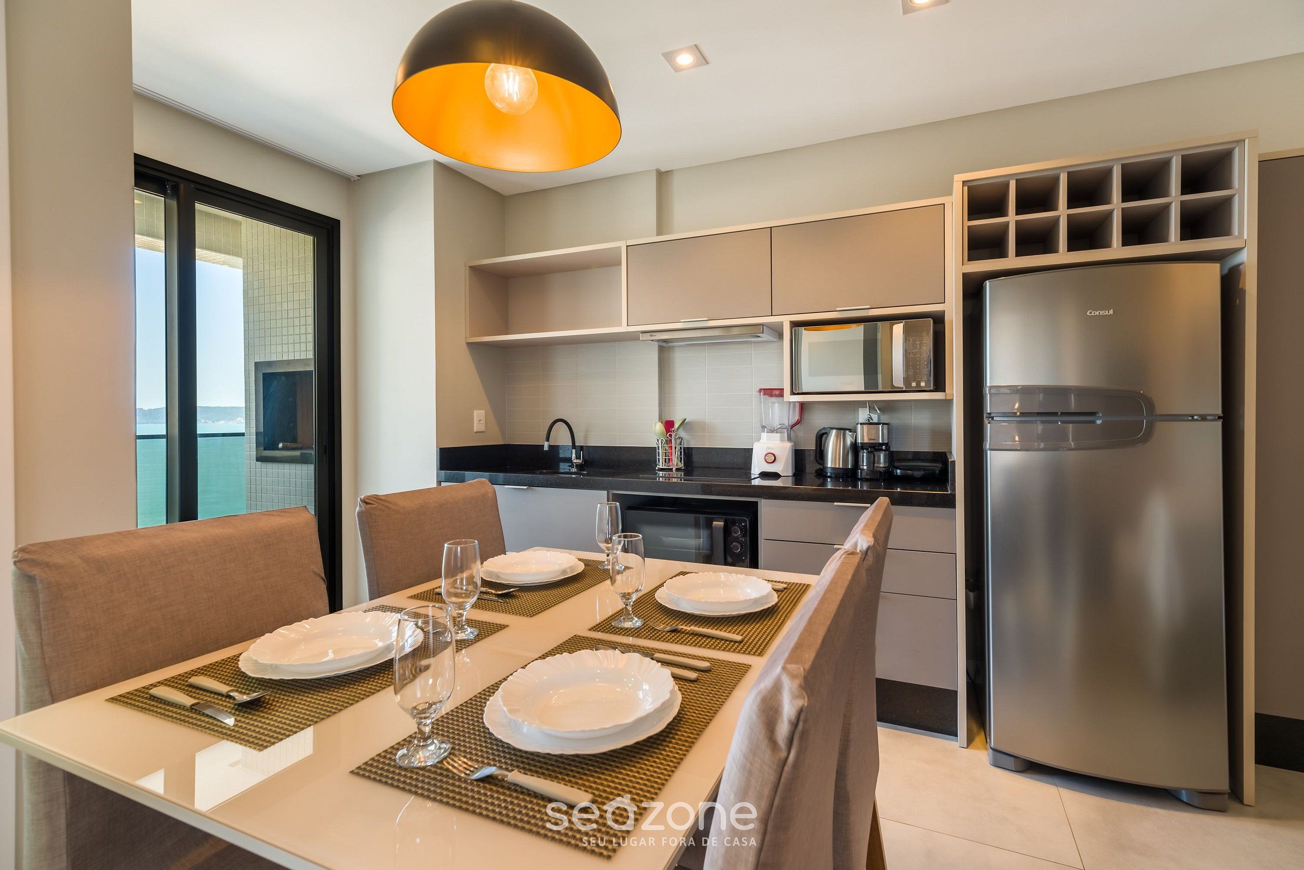 A modern kitchen with a built-in microwave, a stainless steel refrigerator, and a dining area with a table set for two.