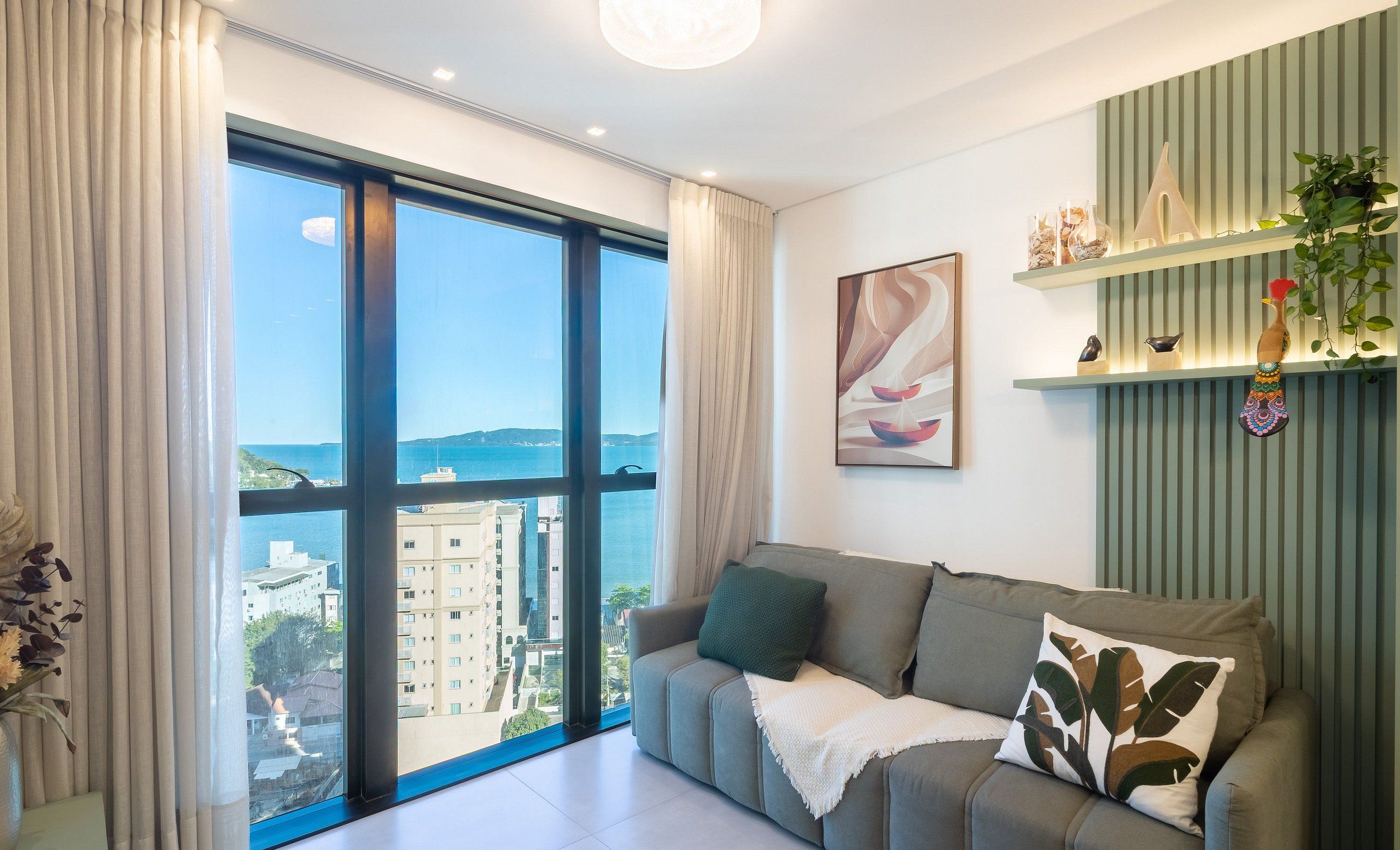 A modern living room with a large window, a sofa, and a decorative shelf.