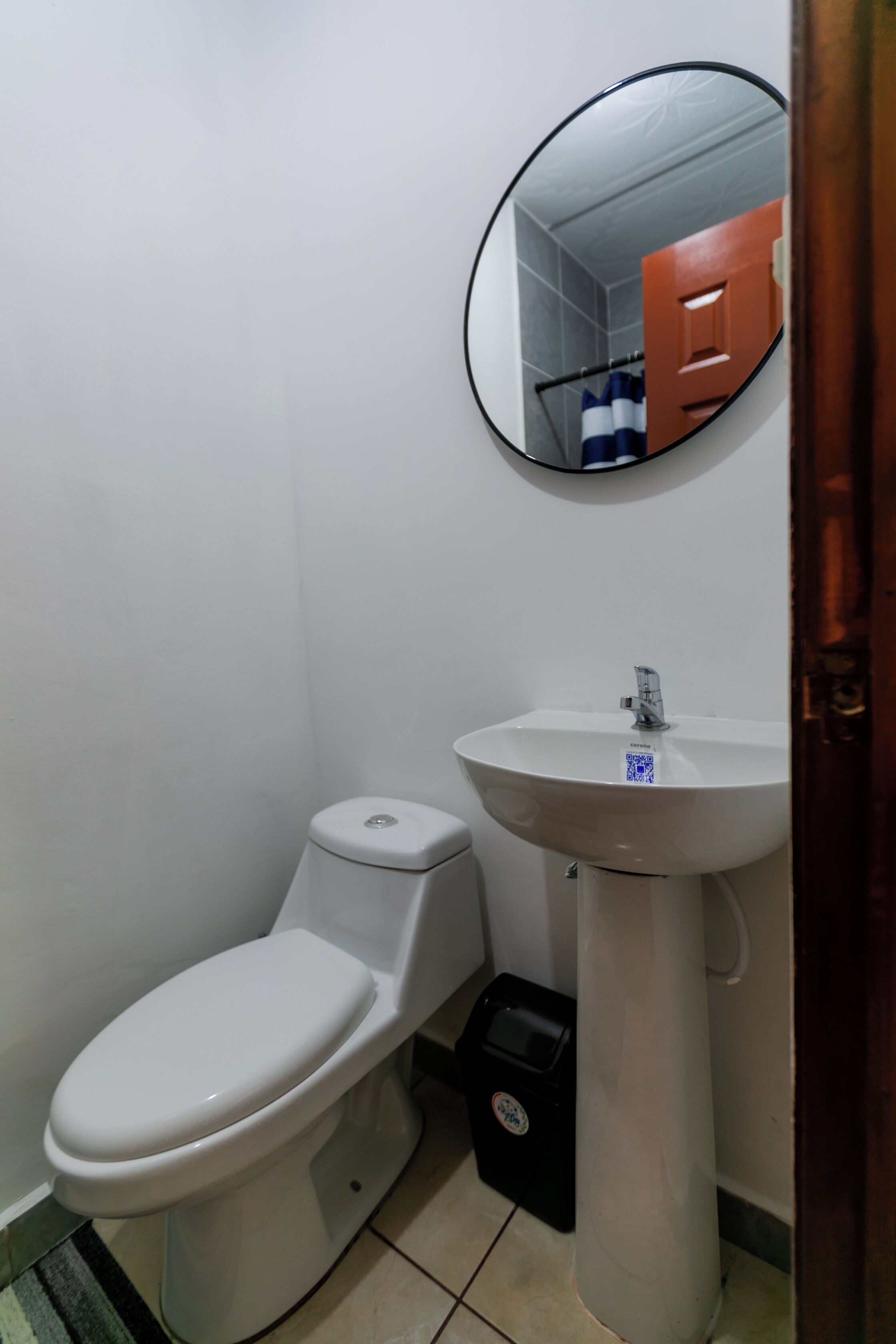 Un baño pequeño con inodoro, lavamanos y espejo.