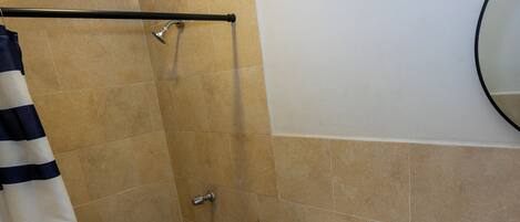 Un baño con ducha, inodoro, lavabo y un perchero a rayas.