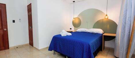 A neatly arranged bedroom with a bed, two bedside tables, a nightstand, and a hanging light fixture.
