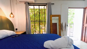 A bedroom with a blue bedspread, a wooden nightstand, a remote control, and a white towel on the bed. - Friendly House (Santa Tecla)