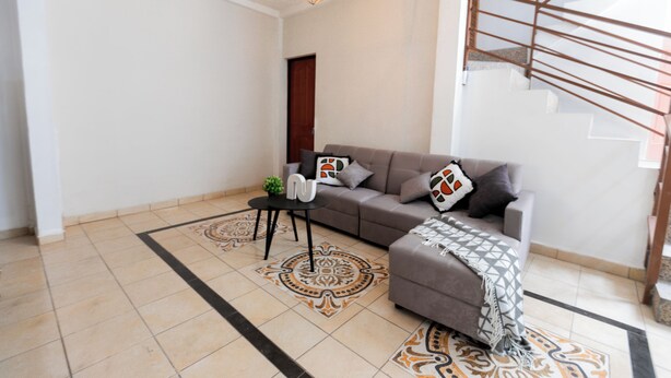 A modern living room with a sofa, coffee table, and patterned rug. - Friendly House (Santa Tecla)