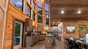 A spacious kitchen with large windows, wooden cabinetry, and a central island. - NEW Canopy Crest Cabin~Indoor Pool~Hot Tub~Game Room (Sevierville)