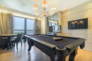 Une table de billard, un lustre, un téléviseur et un coin repas avec vue.