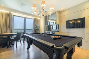 Une table de billard, un lustre, un téléviseur et un coin repas avec vue.