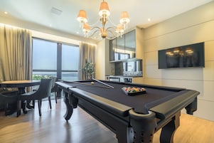 Una mesa de billar con candelabro, televisor y comedor con vistas.