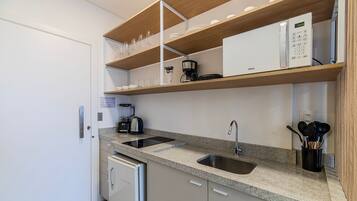 A compact kitchen with a built-in dishwasher, a coffee maker, and a sink.