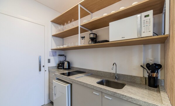 A compact kitchen with a built-in dishwasher, a coffee maker, and a sink. - MHFA Studios em Prédio Luxuoso Vista Mar (Itapema)
