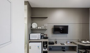 A modern kitchenette with a microwave, coffee maker, and a flat-screen TV mounted on the wall. - MHFA Studios em Prédio Luxuoso Vista Mar (Itapema)
