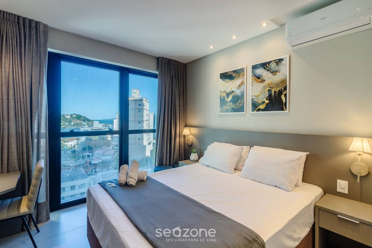 A hotel room with a large bed, a desk, and a view of the city.