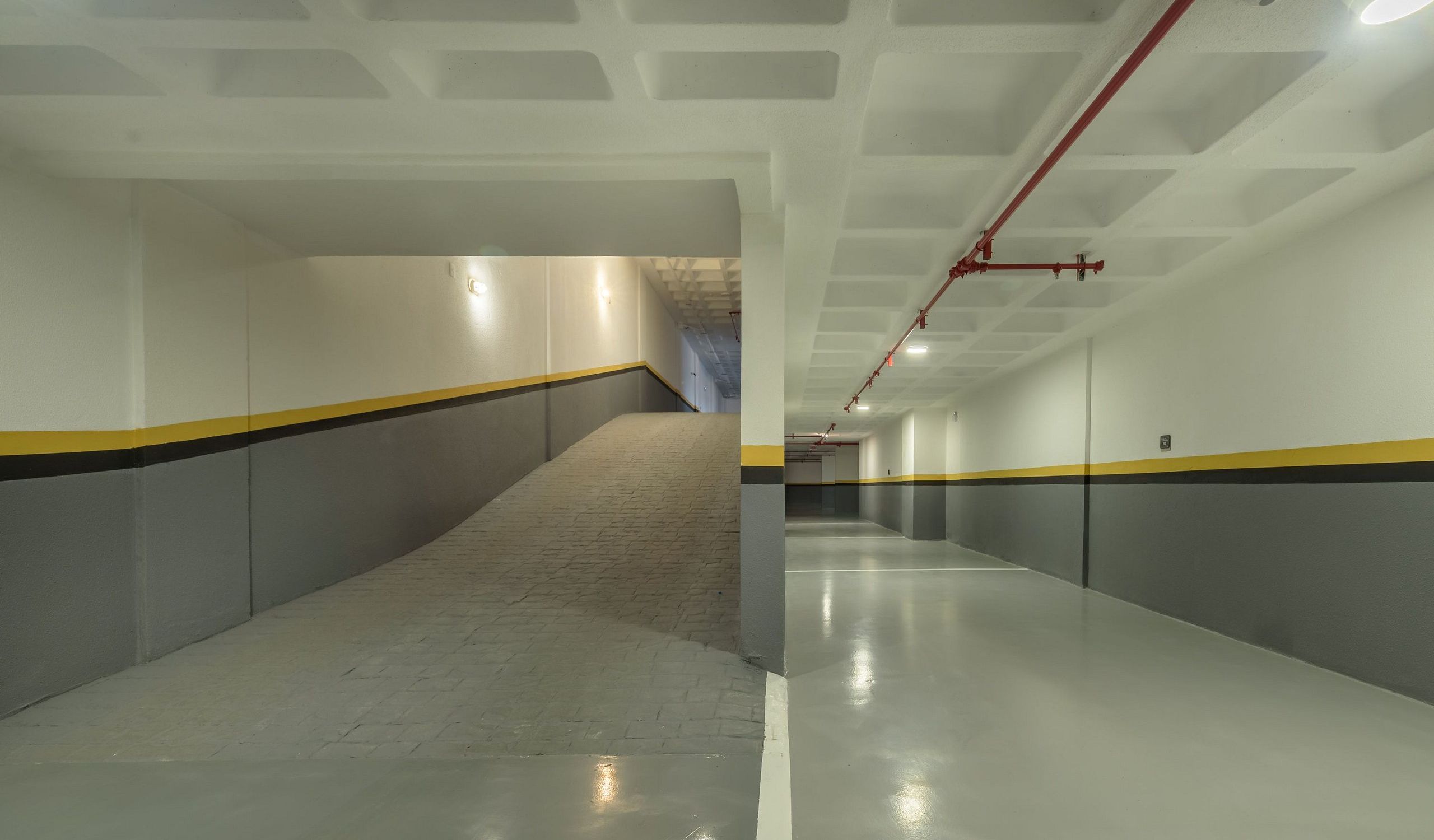 A corridor with a staircase, white walls, and yellow stripes.