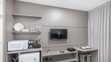 Ein modernes Hotelzimmer mit Flachbildfernseher an der Wand, einer Mikrowelle, einer Kaffeemaschine und einem kleinen Kühlschrank.