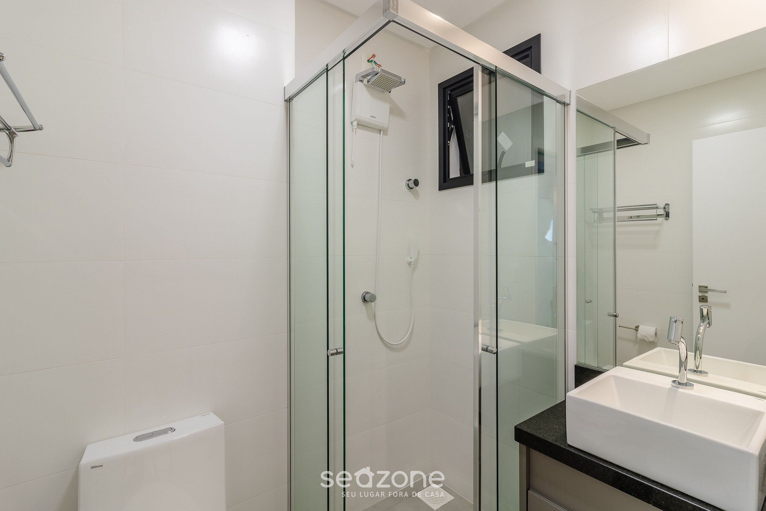 A modern bathroom with a glass-enclosed shower, a white sink, and a large mirror.