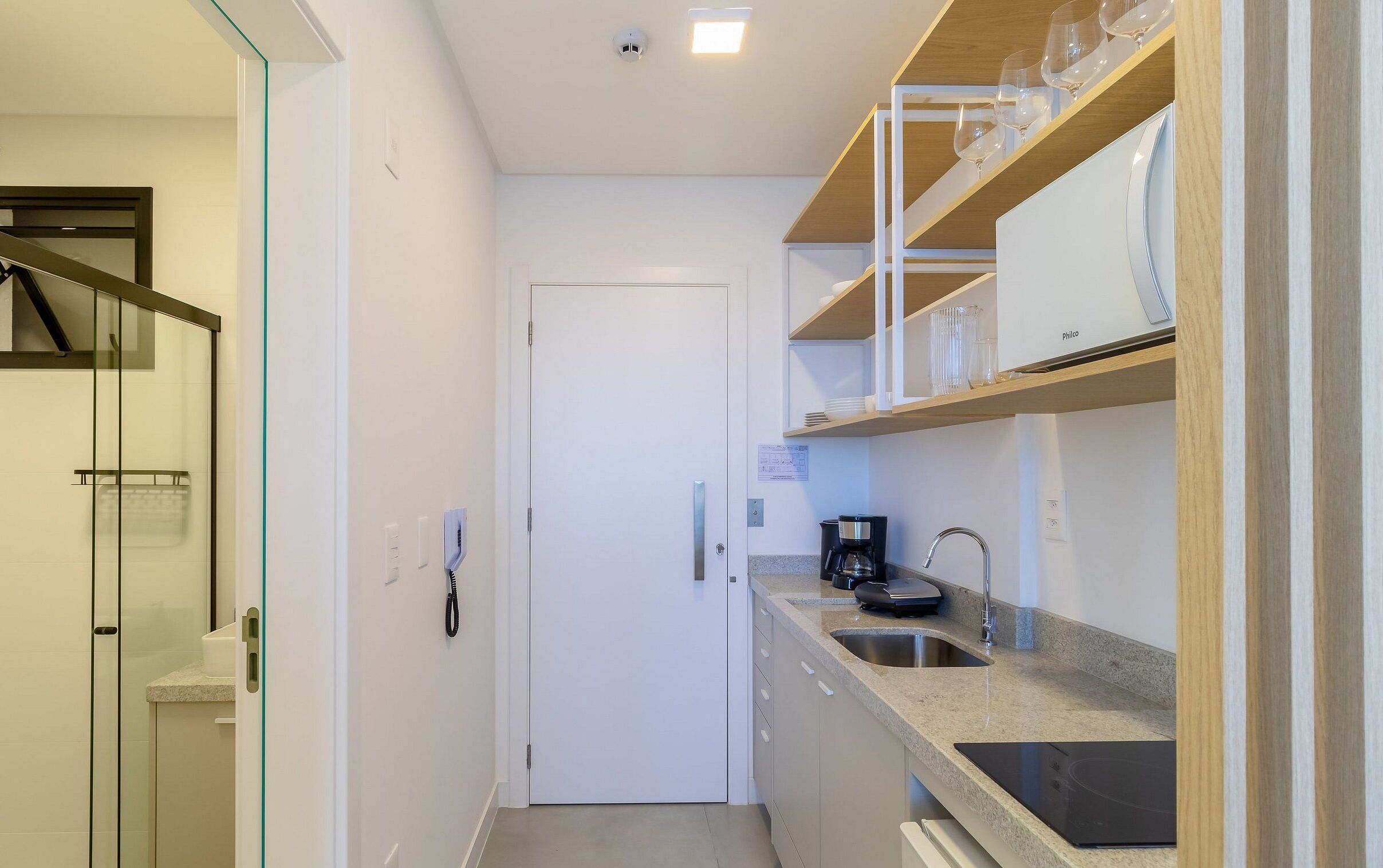 Una cocina compacta con horno integrado, cafetera y espacio para vinos.