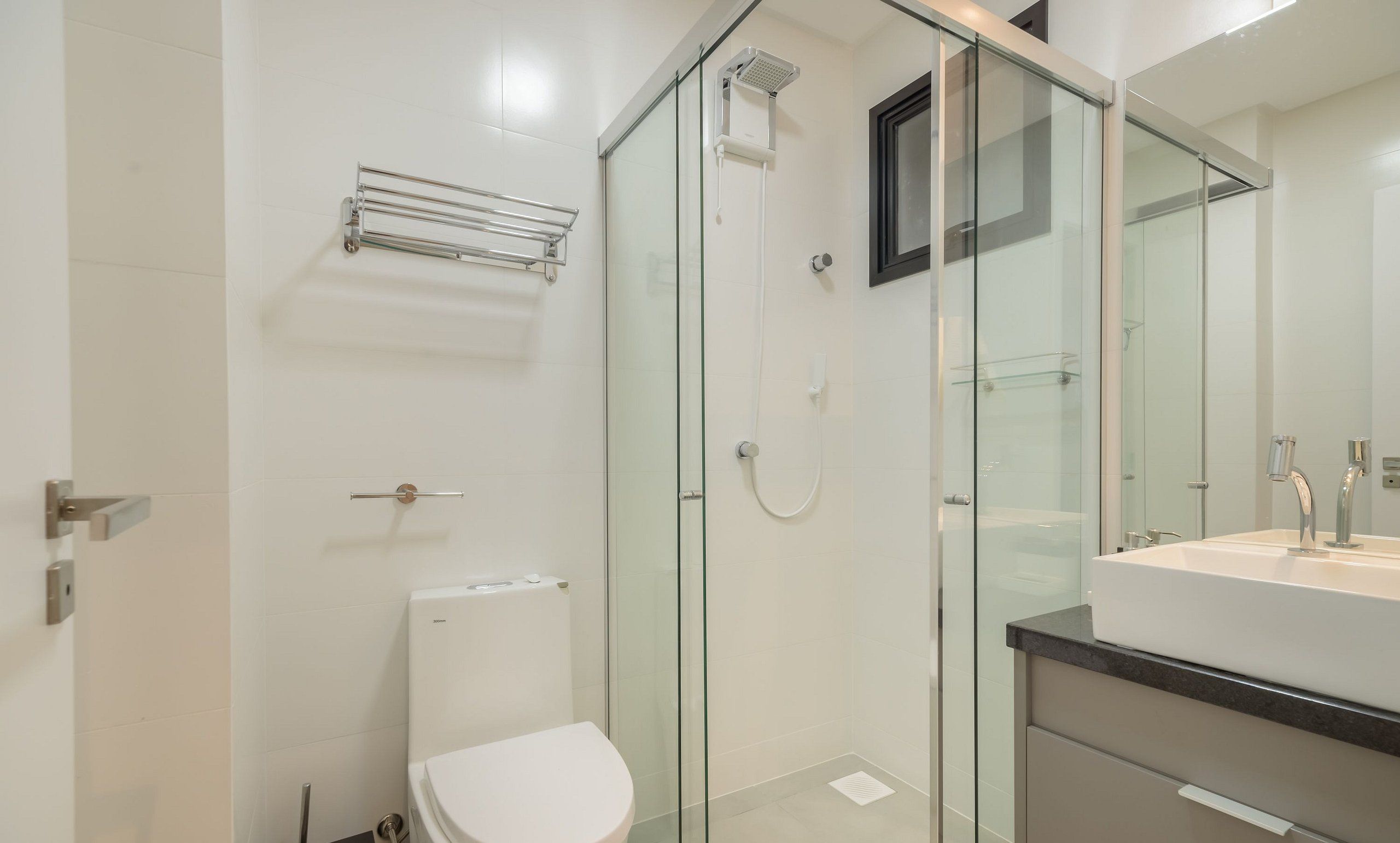 A modern bathroom with a glass shower enclosure, a toilet, and a sink with a mirror.