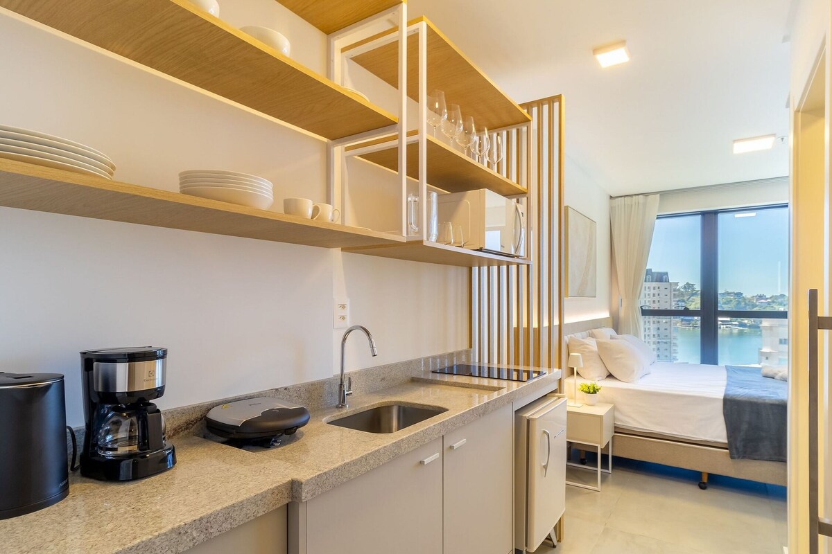 Una cocina moderna con cafetera, lavamanos y refrigerador compacto.