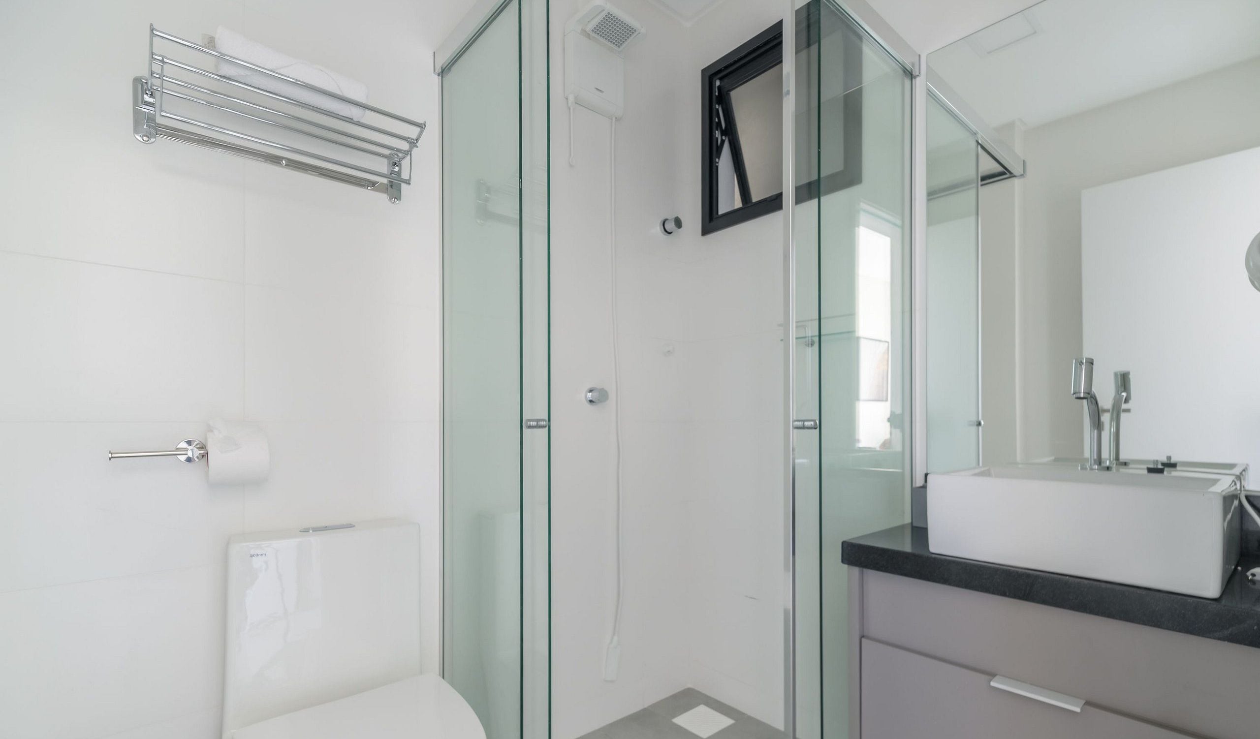 Un baño moderno con cabina de ducha de vidrio, inodoro blanco y tocador con espejo.