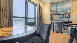 Una cocina moderna con vista al mar, un comedor con mesa y sillas, y una barra con vasos.