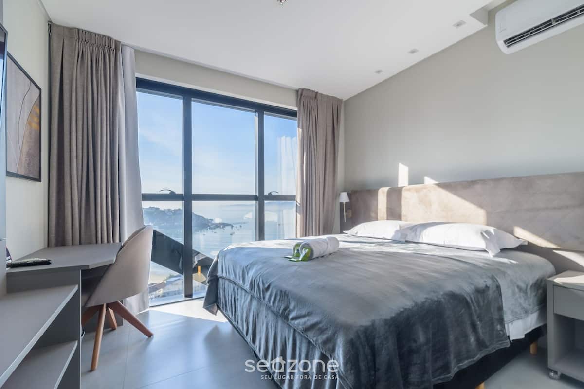 Ett modernt hotellrum med en stor säng, ett skrivbord och utsikt över staden.