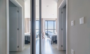 Una habitación de hotel moderna con una cama grande, un escritorio y vistas de la ciudad a través de ventanales de gran altura.