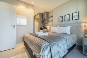Un dormitorio moderno con una cama grande, un armario, una mesita de noche y un estante en la pared con libros.