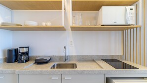 Una cocina moderna con microondas integrado, cafetera y una encimera elegante.