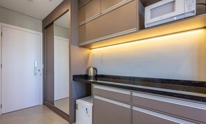 Una cocina moderna con microondas, hervidor y refrigerador.