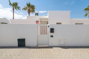 Un edificio blanco con entrada porticada, una placa con número y una ventana pequeña.