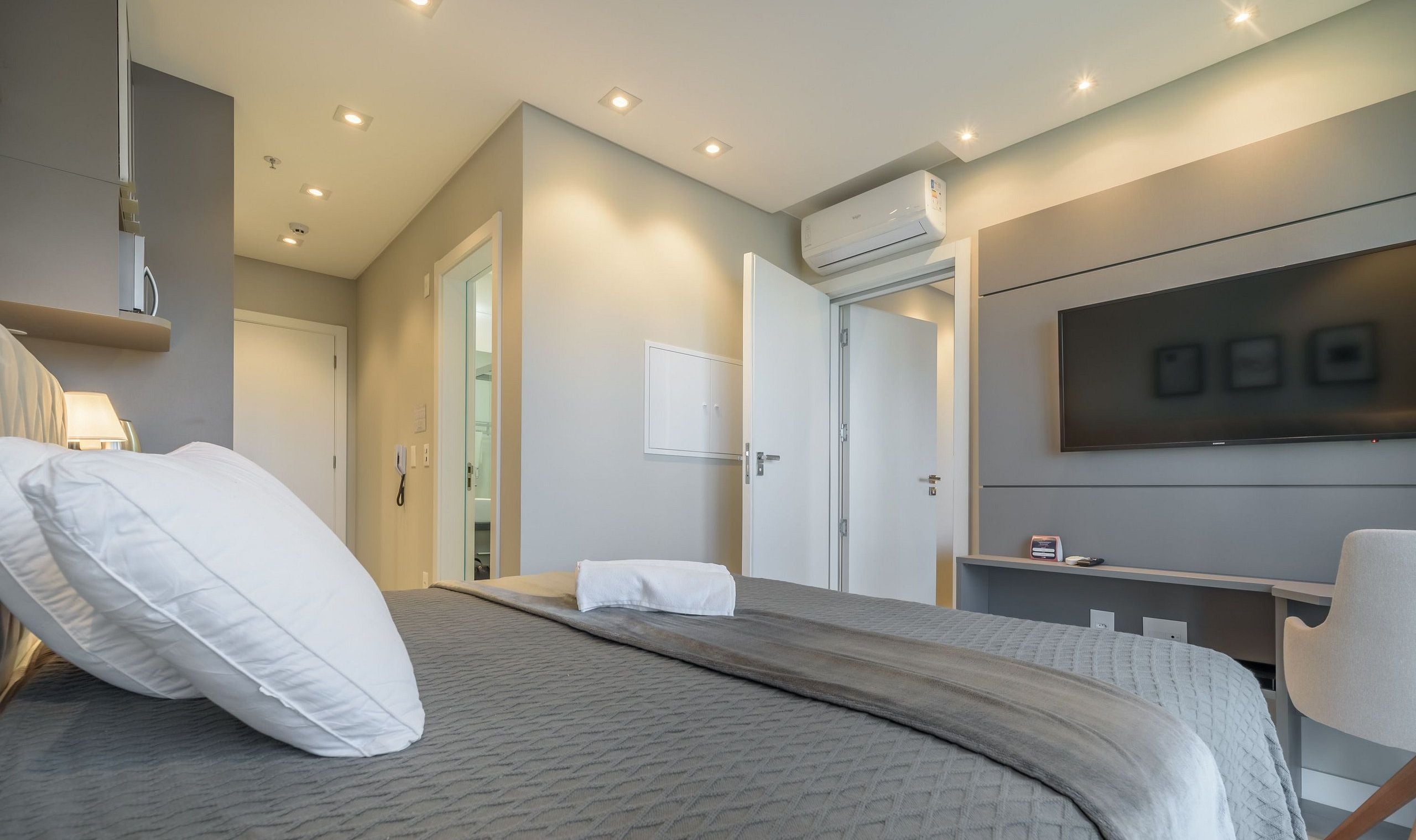 Een moderne hotelkamer met een groot bed, een flatscreen televisie, een airconditioning en een bureau met stoel.