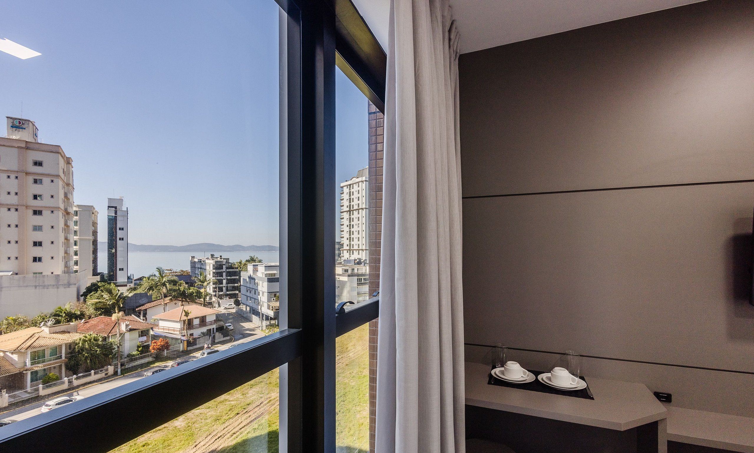 Ein Hotelzimmer mit großem Fenster und Blick auf eine Stadtlandschaft sowie ein Gewässer.