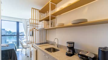 Uma cozinha moderna com micro-ondas integrado, máquina de café e lixeira.