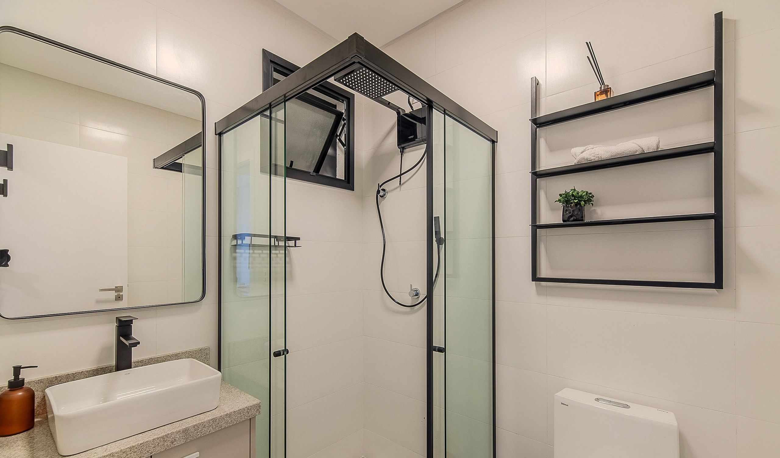 Une salle de bain moderne avec une douche à parois de verre, un lavabo blanc, un miroir et un porte-serviettes.