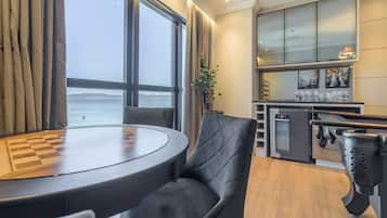 Una cocina moderna con vistas al mar, un comedor con mesa y sillas, y una barra con vasos.
