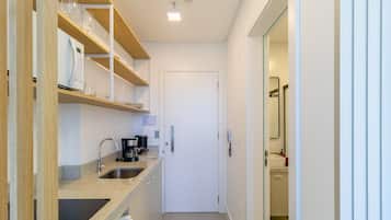 Una cocina compacta con horno integrado, cafetera y lavamanos.