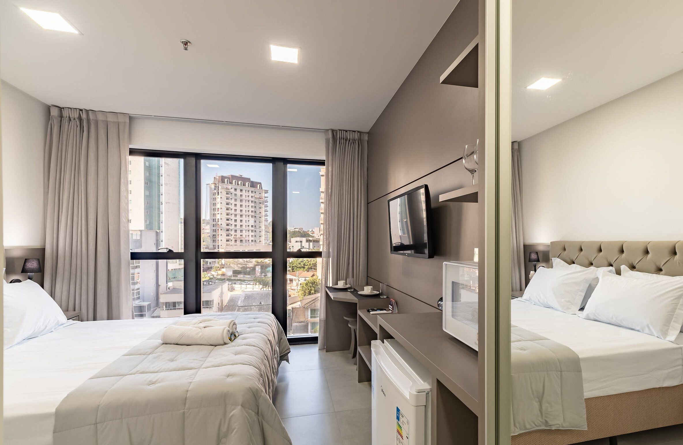 Une chambre d’hôtel avec deux lits, un bureau, une télévision et une vue sur la ville.