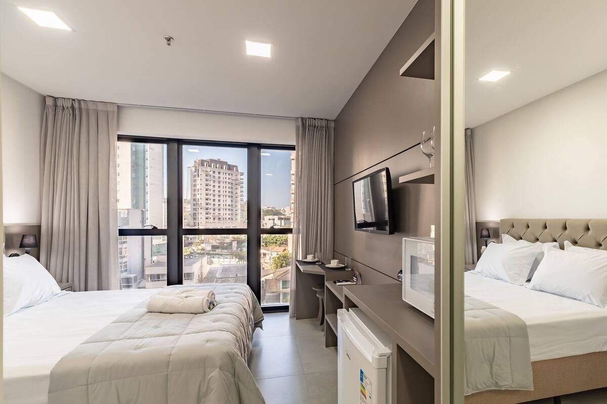 Une chambre d’hôtel avec deux lits, un bureau, une télévision et une vue sur la ville.