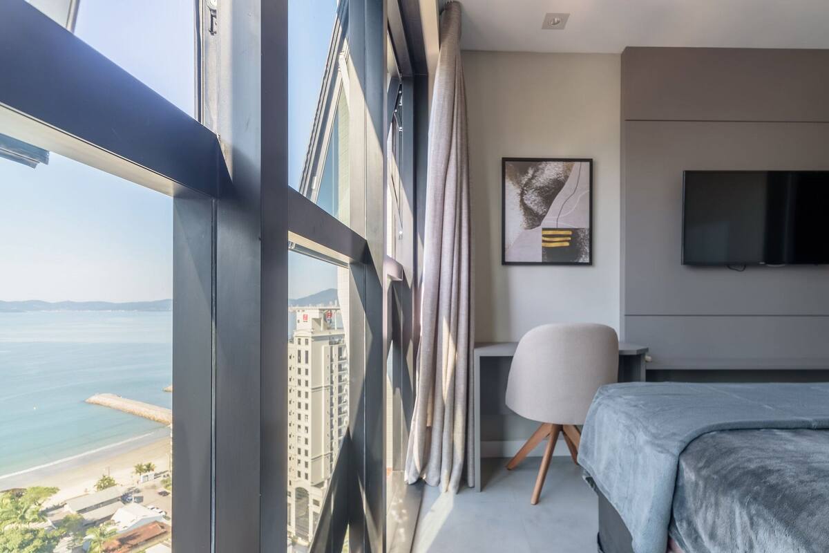 Une chambre d’hôtel moderne dotée d’une grande fenêtre, d’un lit, d’un bureau et d’une télévision.