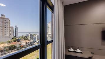 Habitación de hotel con un ventanal grande, vistas a la ciudad y una pequeña zona de estar con una mesa y sillas.