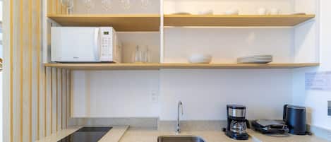 A modern kitchen with a microwave, coffee maker, and a sink.