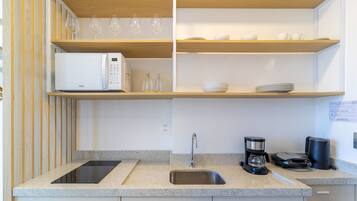 Uma cozinha moderna com micro-ondas, cafeteira e pia.