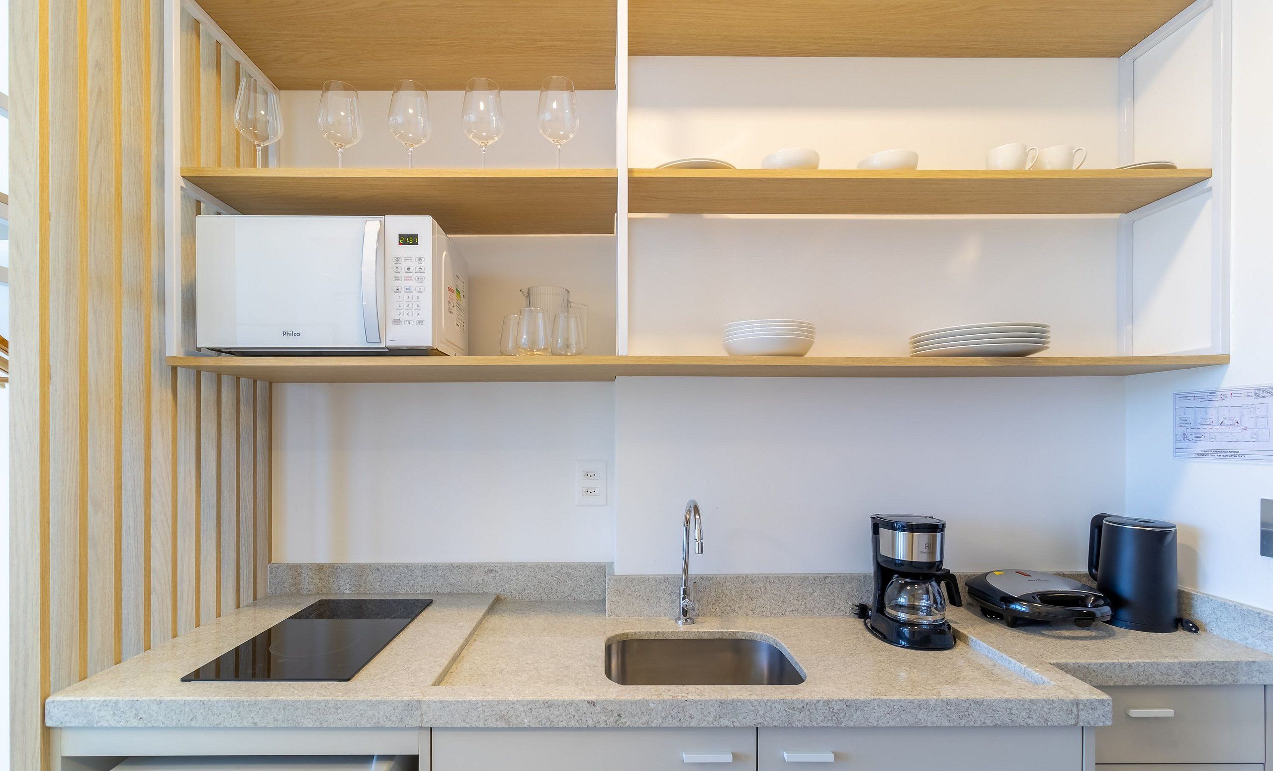 A modern kitchen with a microwave, coffee maker, and a sink.