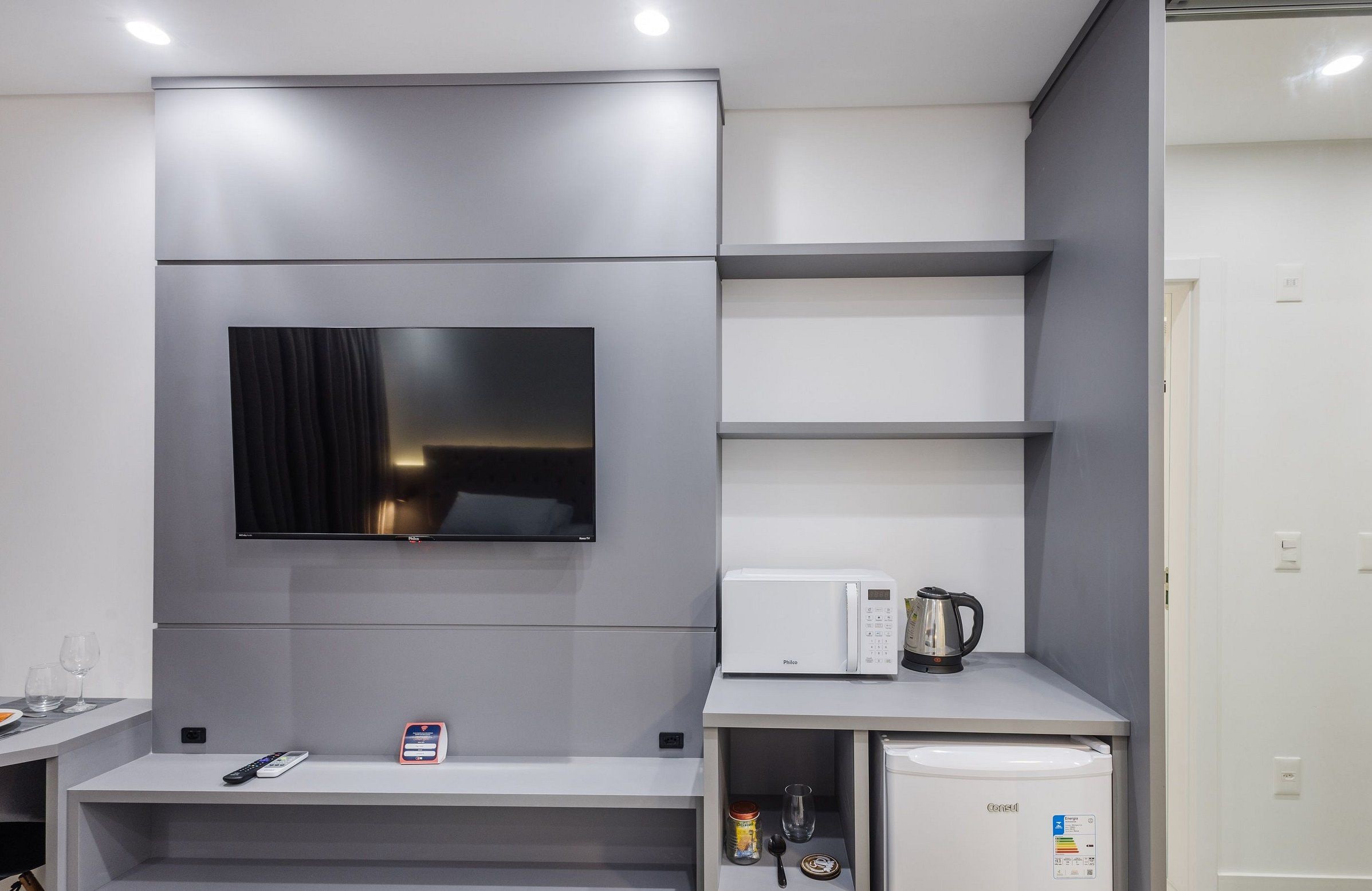 A modern kitchen with a built-in TV, a coffee maker, and a mini-fridge.