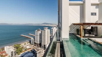 Um edifício alto com piscina, com vista para a paisagem urbana costeira.