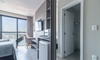 Una habitación de hotel moderna con cama, escritorio, televisor y vistas a la ciudad.