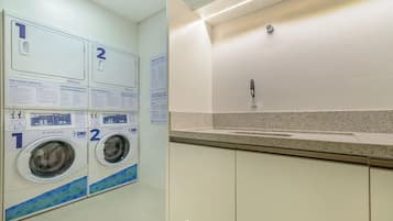 A laundry area with two washing machines, numbered signs, and informational posters.