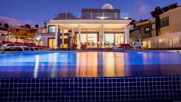 Un hotel moderno con piscina, zona de estar al aire libre y un edificio grande de techo plano.