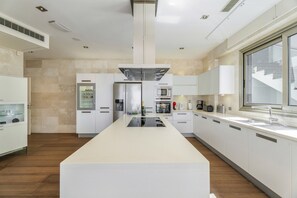 Une cuisine moderne dotée d’un îlot central, d’appareils électroménagers intégrés et d’une grande fenêtre.