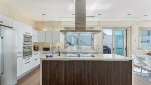 Una cocina moderna con una isla central, electrodomésticos integrados y vistas al exterior.