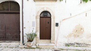 Un bâtiment avec une porte marron, un pot de fleurs et un mur blanc.
